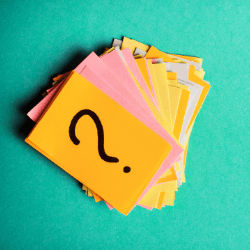 a stack of post-it notes with a question mark on the top note